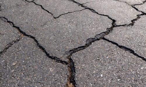 Damaged asphalt showing wear and large cracks